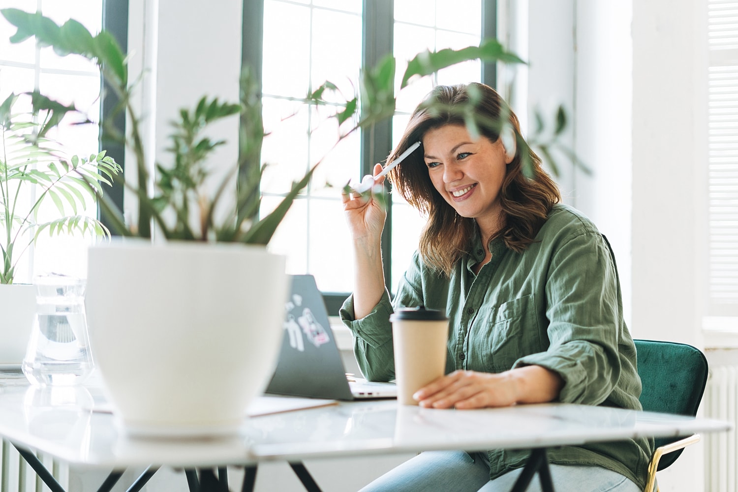 Smiling woman working at a desk with plants.
