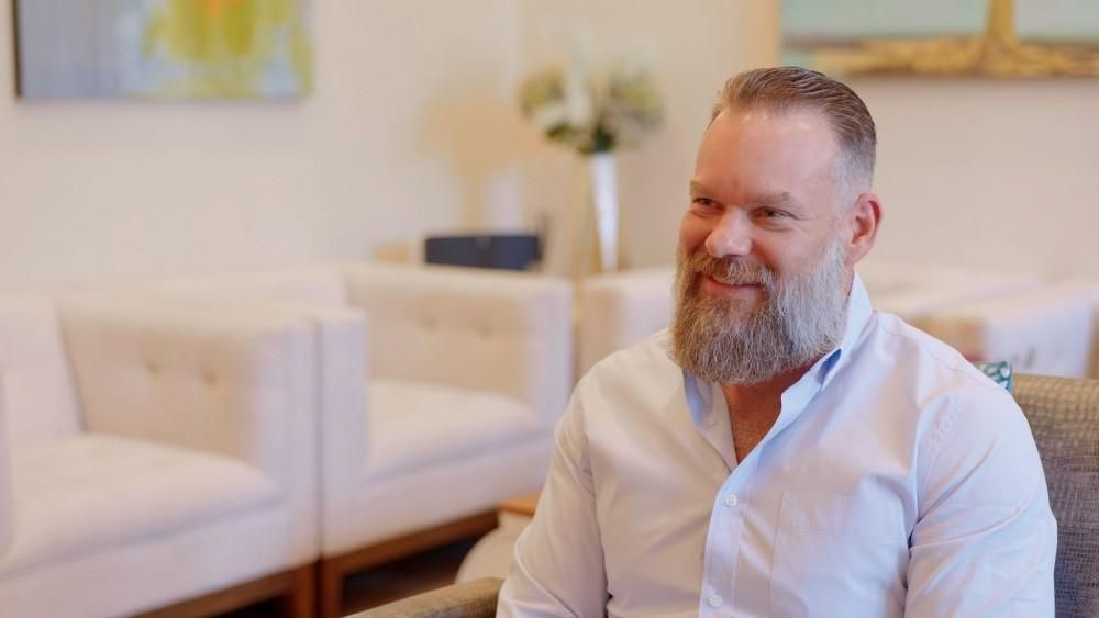 Man smiling in a cozy, well-furnished setting.