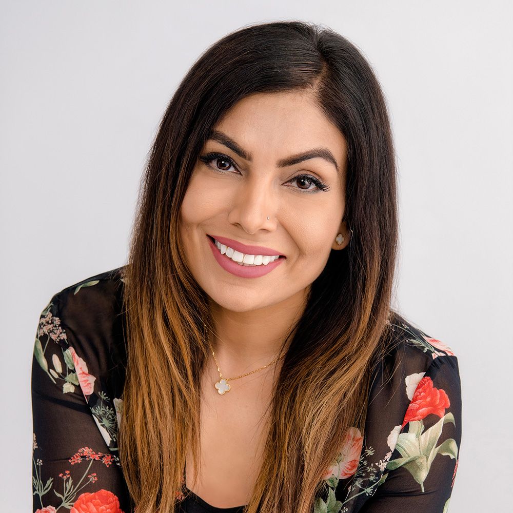 Smiling woman with long, dark hair and floral shirt.