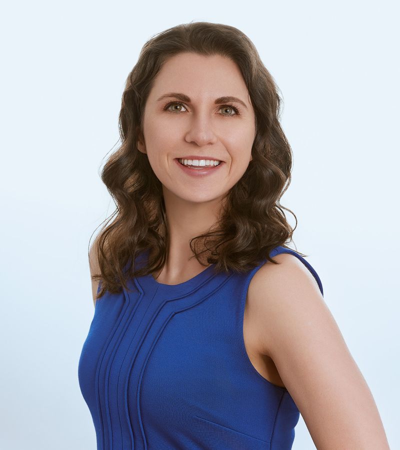 Smiling woman in a blue dress, light background.