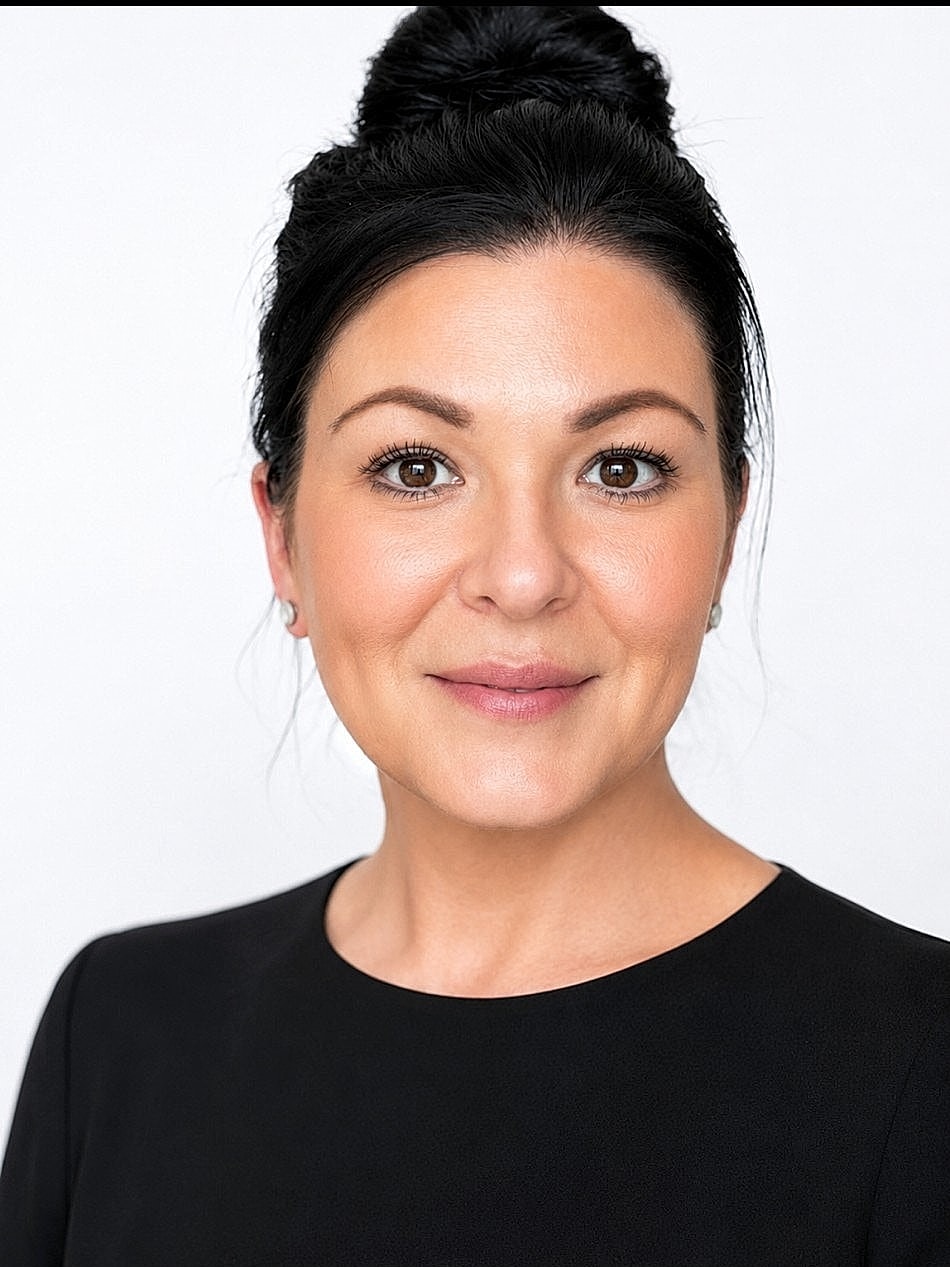 Woman with dark hair, smiling against white background.